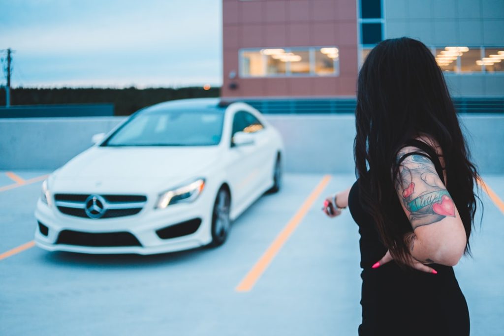woman in black jacket standing near white car during daytime