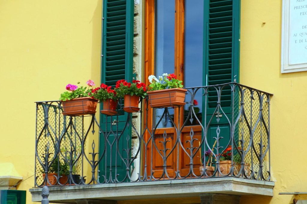 Pot de géraniums fleuris accroché à une rambarde de balcon