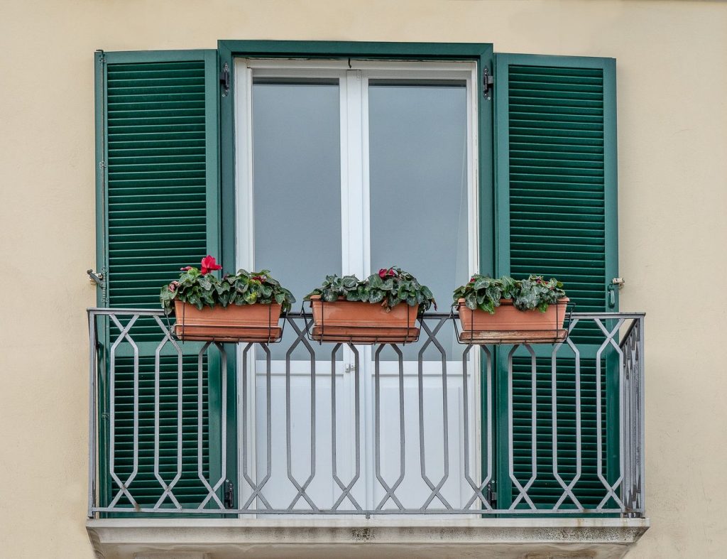 Des pots suspendus accrochés à une rambarde de balcon.