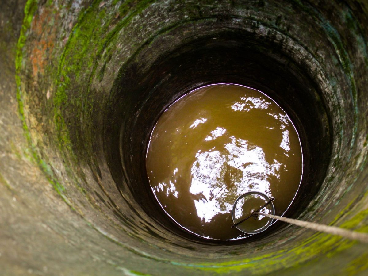 Puits domestique en pierre, eau visible au fond avec seau sur corde