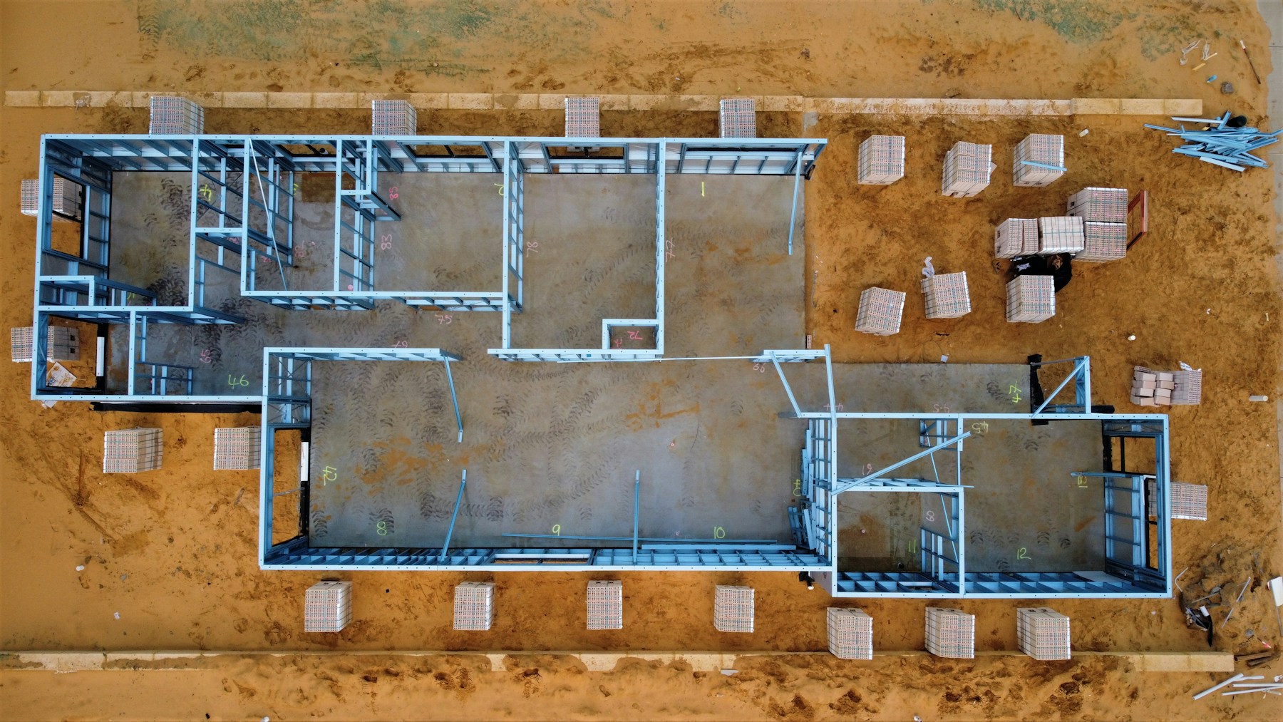 vue aérienne d'une extension de maison en cours de construction avec ossature métallique posée sur une dalle