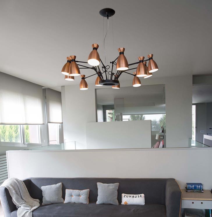 Lustre industriel cuivré à plusieurs bras suspendu au-dessus d'un canapé gris